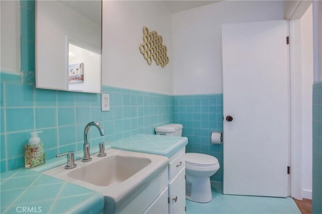 bathroom with vanity, tile walls, and toilet