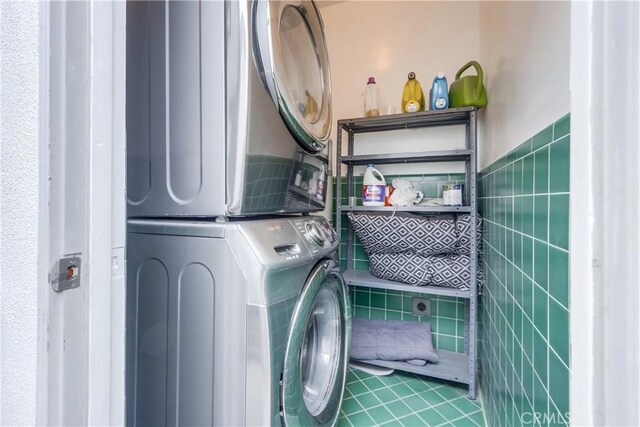 laundry room featuring tile walls and stacked washer / drying machine