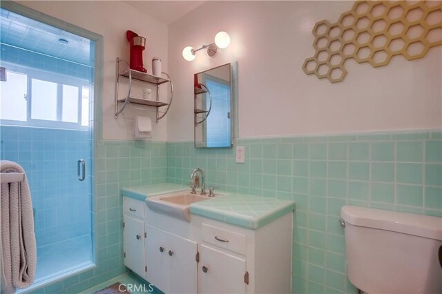 bathroom with tile walls, vanity, a shower with shower door, and toilet