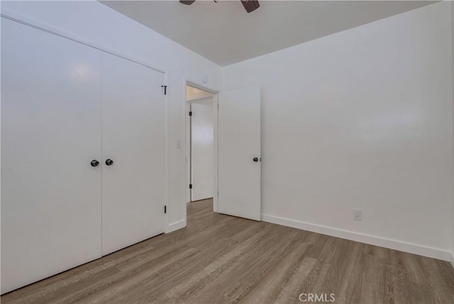 unfurnished bedroom with ceiling fan, light hardwood / wood-style floors, and a closet