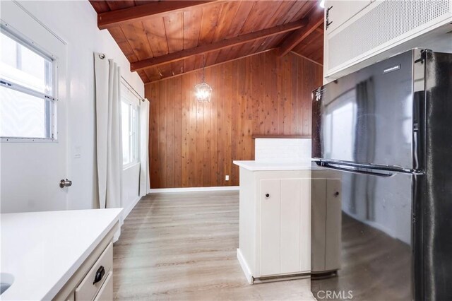 kitchen with black refrigerator, lofted ceiling with beams, white cabinets, wooden ceiling, and light wood-type flooring