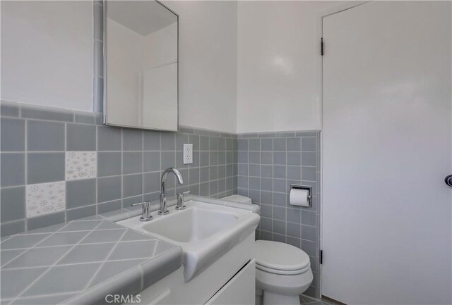 bathroom with vanity, tile walls, and toilet