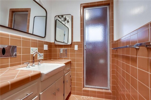 bathroom with vanity, tile walls, and a shower