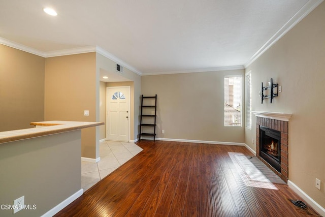 unfurnished living room with light wood-type flooring, crown molding, and a fireplace