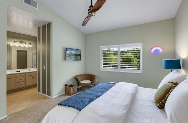 bedroom with connected bathroom, light carpet, baseboards, lofted ceiling, and visible vents