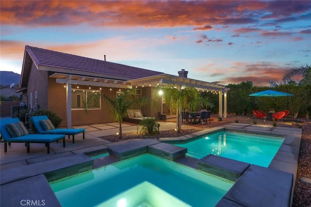 pool at dusk with a patio, a pergola, and an in ground hot tub