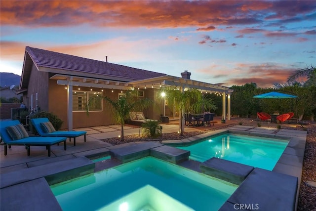 pool at dusk featuring a patio area, a pool with connected hot tub, and a pergola