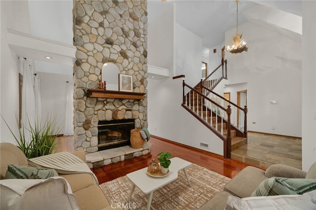 living room featuring a fireplace, hardwood / wood-style flooring, high vaulted ceiling, and a chandelier