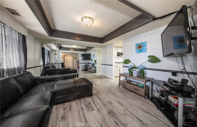 living room featuring light hardwood / wood-style flooring, a textured ceiling, and a raised ceiling