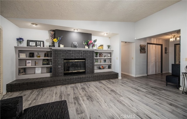 living room featuring a brick fireplace, a textured ceiling, lofted ceiling, and hardwood / wood-style floors