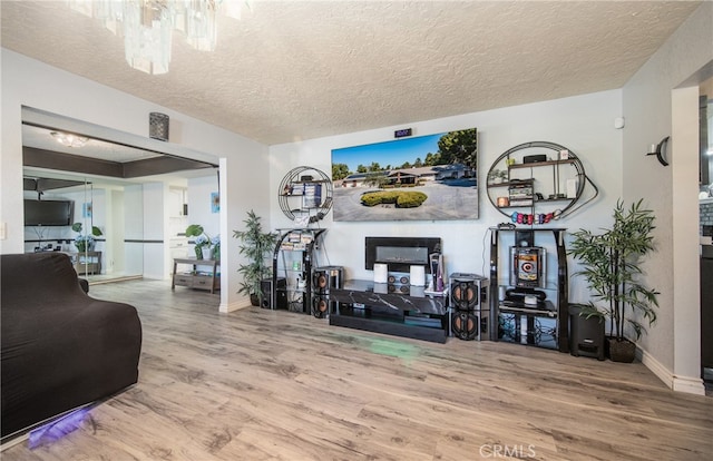 living room featuring wood-type flooring, a textured ceiling, and a chandelier