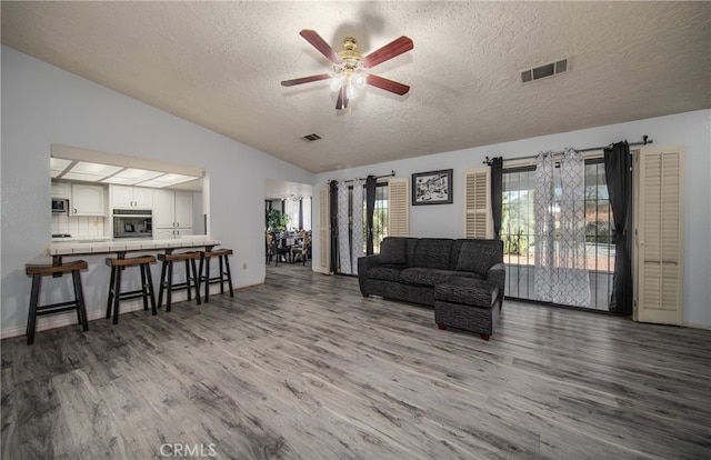 living room featuring a textured ceiling, lofted ceiling, dark hardwood / wood-style floors, and ceiling fan