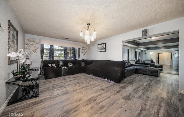 living room featuring a notable chandelier, a textured ceiling, and hardwood / wood-style floors