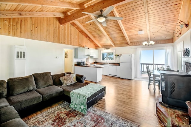 living room with light hardwood / wood-style floors, sink, ceiling fan with notable chandelier, beam ceiling, and high vaulted ceiling