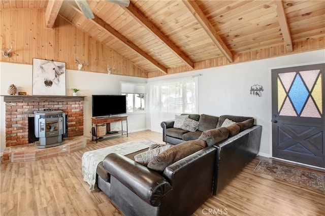 living room featuring vaulted ceiling with beams, wood ceiling, light hardwood / wood-style flooring, and a wood stove