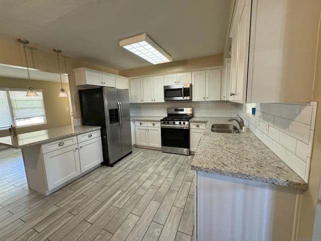 kitchen with sink, light wood-type flooring, white cabinetry, stainless steel appliances, and decorative light fixtures