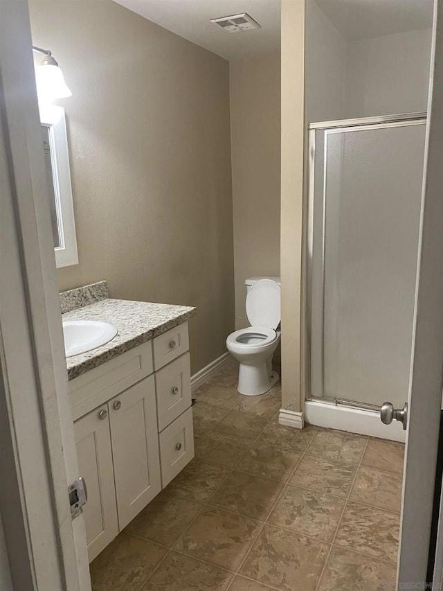 bathroom featuring vanity, a shower with shower door, and toilet