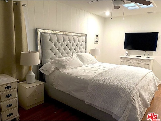 bedroom with wooden walls, dark hardwood / wood-style flooring, and ceiling fan