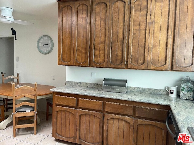 kitchen with light stone countertops, ceiling fan, light tile patterned flooring, and dishwashing machine