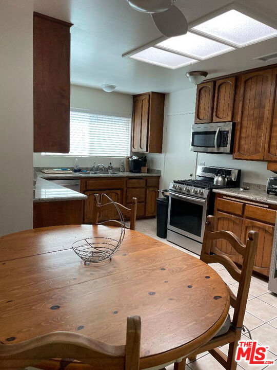 kitchen featuring stainless steel appliances, light tile patterned floors, and sink