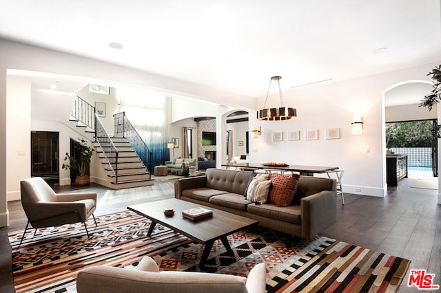 living room with a chandelier, a fireplace, and dark wood-type flooring