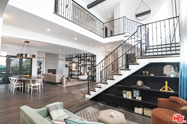 living room featuring a fireplace, a towering ceiling, and hardwood / wood-style flooring