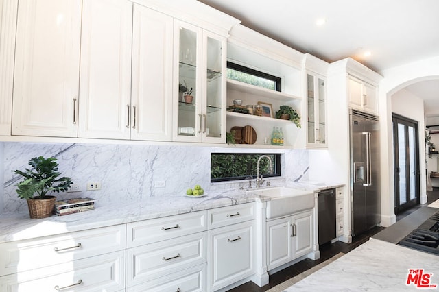 kitchen with white cabinets, decorative backsplash, light stone countertops, and stainless steel appliances