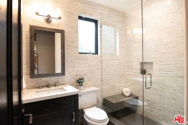 bathroom featuring walk in shower, vanity, toilet, and tile walls