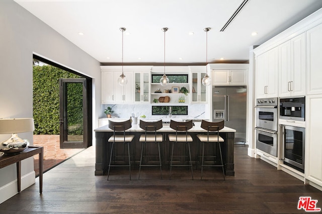 kitchen featuring appliances with stainless steel finishes, a center island, white cabinetry, and pendant lighting