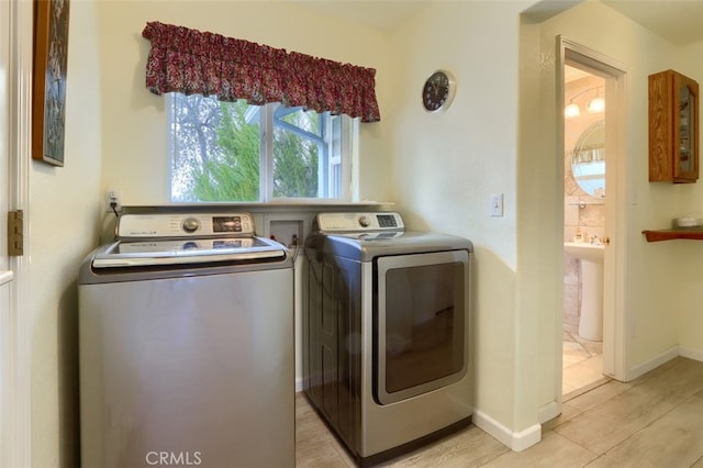 laundry area with light wood-type flooring, washer and clothes dryer, and sink