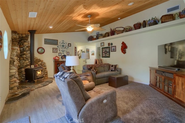 living room featuring ceiling fan, a wood stove, light hardwood / wood-style flooring, wooden ceiling, and vaulted ceiling