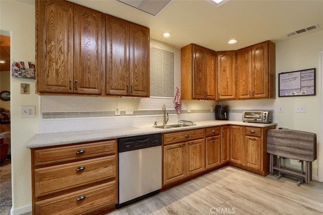 kitchen with light wood-type flooring, dishwasher, light stone counters, sink, and backsplash