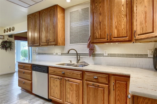 kitchen with light stone counters, sink, dishwasher, light hardwood / wood-style floors, and decorative backsplash