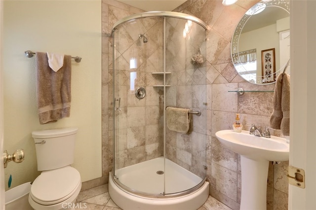 bathroom featuring toilet, sink, tile patterned floors, and a shower with shower door