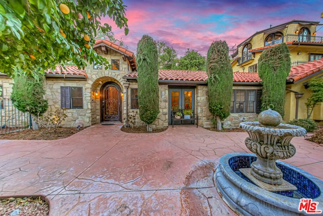 mediterranean / spanish house featuring a patio area and french doors