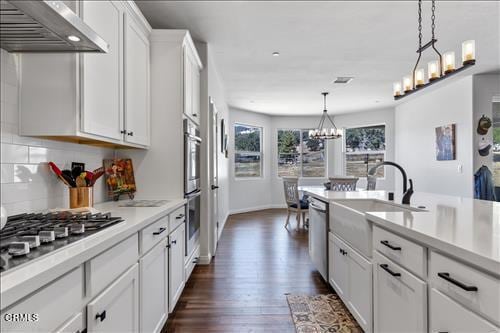 kitchen featuring pendant lighting, white cabinets, exhaust hood, stainless steel appliances, and dark hardwood / wood-style flooring