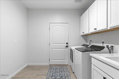 laundry room with washer and clothes dryer, light hardwood / wood-style flooring, and cabinets