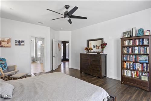 bedroom with ceiling fan, ensuite bath, and dark hardwood / wood-style flooring