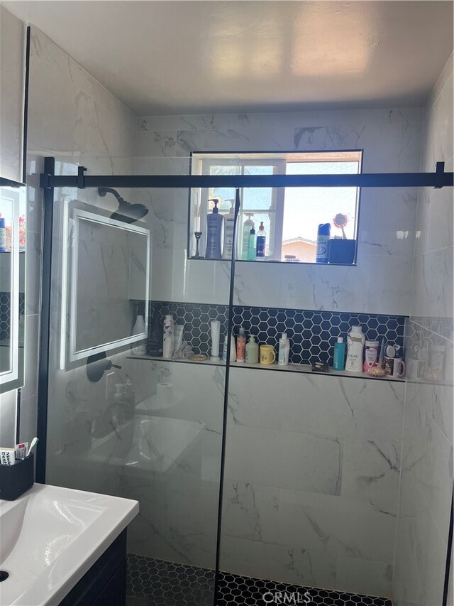 bathroom with a tile shower and vanity