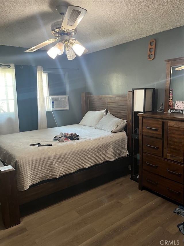 bedroom with ceiling fan, cooling unit, a textured ceiling, and dark wood-type flooring