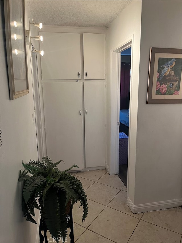 corridor with a textured ceiling and light tile patterned floors