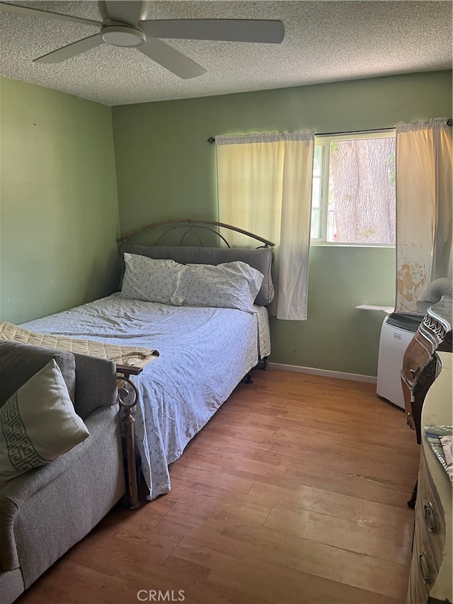 bedroom featuring wood-type flooring, ceiling fan, and a textured ceiling