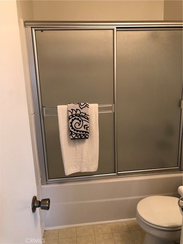 bathroom featuring tile patterned flooring, shower / bath combination with glass door, and toilet