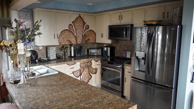 kitchen with backsplash, sink, cream cabinets, and appliances with stainless steel finishes