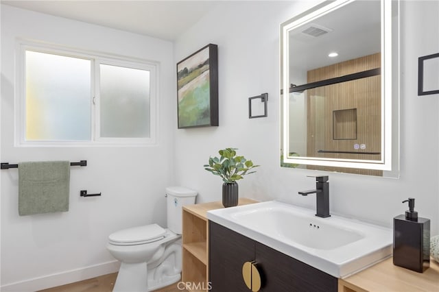 bathroom featuring hardwood / wood-style flooring, vanity, toilet, and a shower with shower door