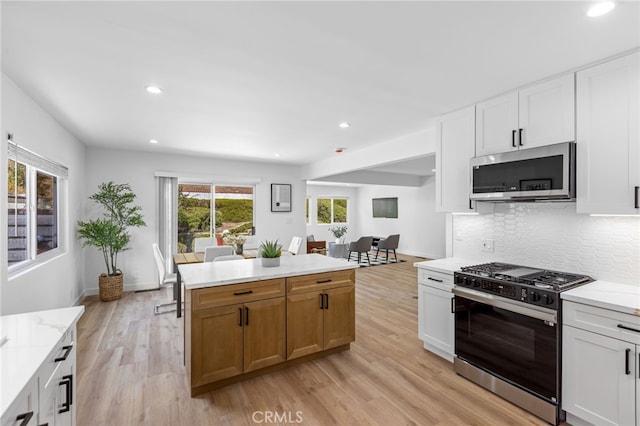 kitchen featuring light stone countertops, appliances with stainless steel finishes, light hardwood / wood-style flooring, and white cabinetry