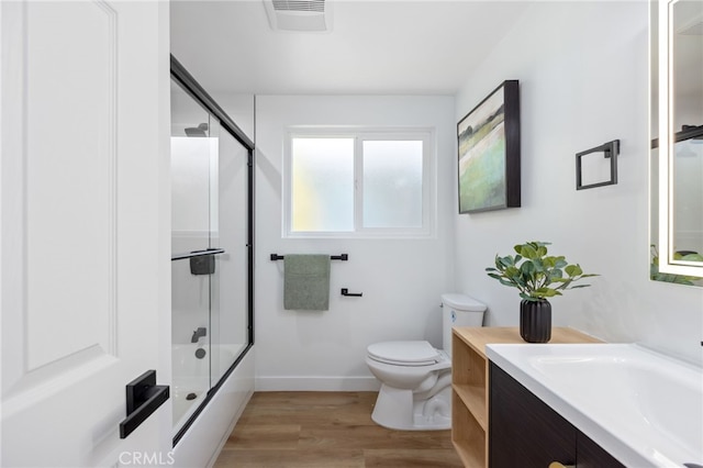 full bathroom featuring shower / bath combination with glass door, vanity, wood-type flooring, and toilet