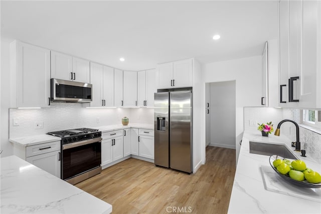 kitchen featuring light stone countertops, sink, white cabinets, and stainless steel appliances