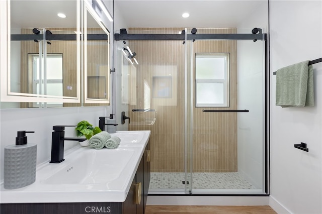 bathroom featuring hardwood / wood-style floors, vanity, and a shower with door