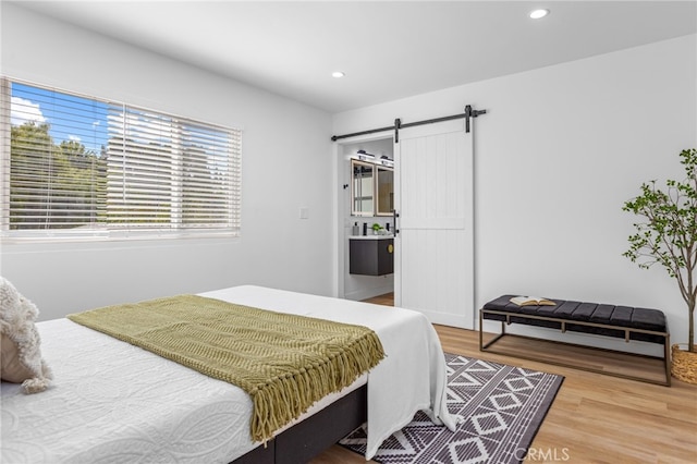 bedroom featuring a barn door and hardwood / wood-style flooring